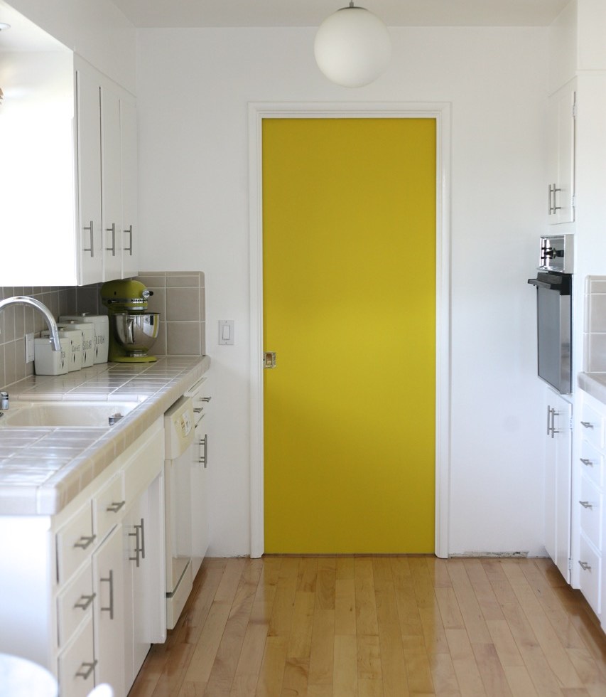 yellow pocket door kitchen mid century white cabinets wood floor