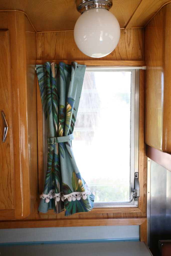 Shasta trailer vintage interior kitchen window bark cloth curtains globe light turquoise counters